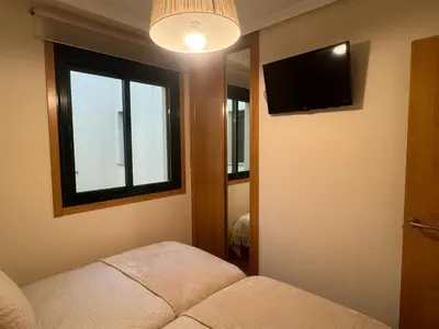 a room with a couch and a tv and a window at Costa SPA Ático de lujo - Playa de las Catedrales in San Miguel de Reinante