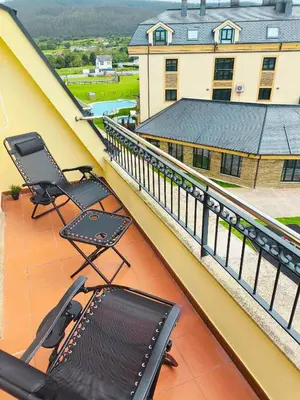 a balcony with two chairs and a table on a building at Costa SPA Ático de lujo - Playa de las Catedrales in San Miguel de Reinante