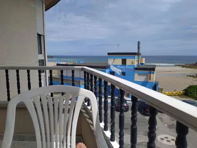 a white chair on a balcony with a view of the beach at Vivienda PLAYA DE ALTAR in Barreiros