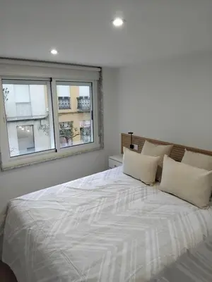 a bedroom with a large white bed with two windows at Sita in A Estrada