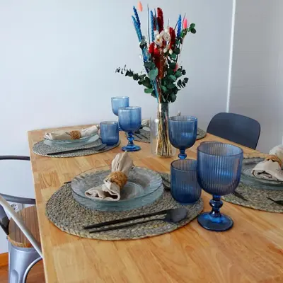 a table with blue glasses and a dog laying on a plate at Atalaia Apartment Foz in Foz