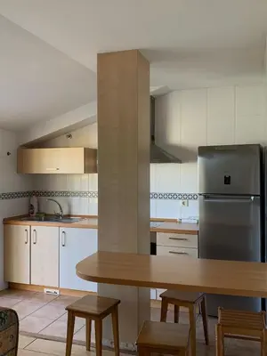 a kitchen with a wooden table and a refrigerator at Rincón de Noa in Melide
