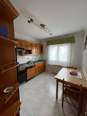 a kitchen with wooden cabinets and a table in it at O Carballal in A Pontenova