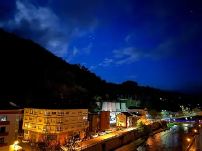 a city at night with a river and buildings at Tres Ruas in A Pontenova