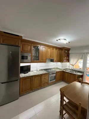a kitchen with wooden cabinets and a stainless steel refrigerator at Tres Ruas in A Pontenova