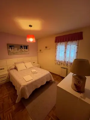 a bedroom with a bed and a table with a lamp at Tres Ruas in A Pontenova