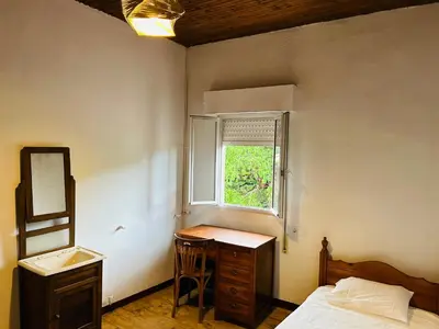 a bedroom with a bed and a desk and a window at Casa Cerdeira Ribeira Sacra in Monforte de Lemos