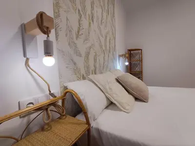a bedroom with a white bed with a lamp and a chair at La glorieta del Miño in Ourense