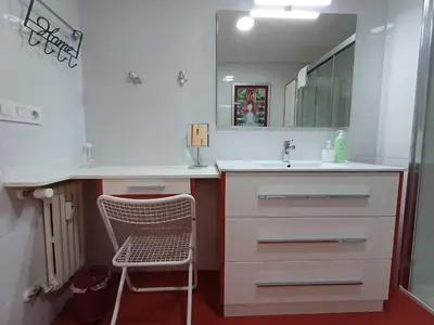 a white bathroom with a sink and a chair at La glorieta del Miño in Ourense