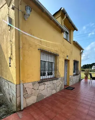 a yellow house with a stone wall and a balcony at El polvorín in El Franco