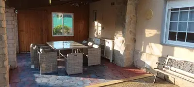 a patio with a table and wicker chairs in a house at Lama de María in Ourense