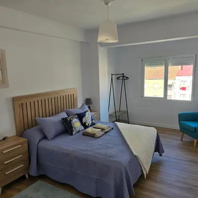 a bedroom with a bed with blue pillows and a window at piso libertad in Ourense