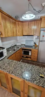 a kitchen with wooden cabinets and a granite counter top at El Mirador de Covas - 2 Hab - Garaje in Covas