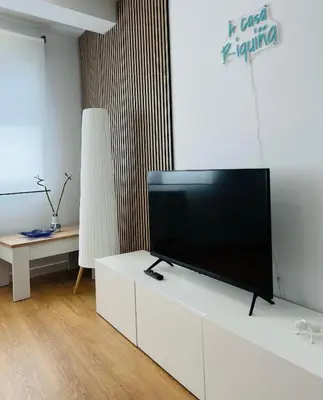 a living room with a flat screen tv on a white cabinet at A Casa Riquiña in Lugo