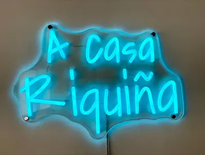 a neon sign that reads a cacca raciulum at A Casa Riquiña in Lugo