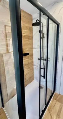 a glass shower door in a room with wood at A Casa Riquiña in Lugo