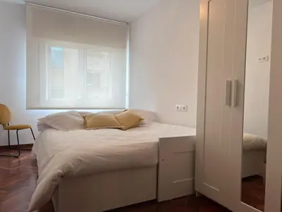 a white bedroom with a bed and a window at Abaleen apartamento in Sigüeiro