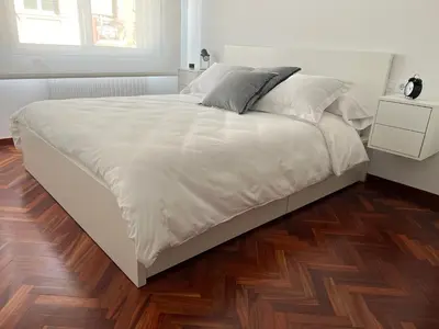 a white bed in a bedroom with a wooden floor at Abaleen apartamento in Sigüeiro