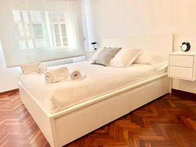 a large white bed in a room with a window at Abaleen apartamento in Sigüeiro