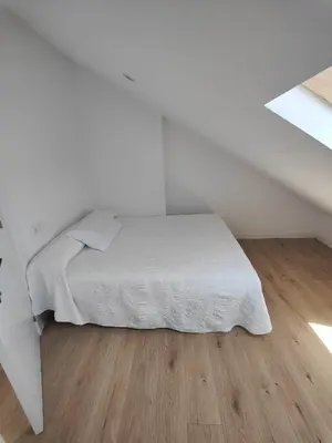 a bed in a white room with a wooden floor at Chalet con WIFI , PS4 , garaje, 5 dormitorios, 3 baños, Santiago de Compostela in Santiago de Compostela