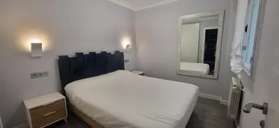 a small bedroom with a white bed and a mirror at Las Gaviotas in Viveiro