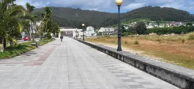 a person walking down a sidewalk with a street light at Las Gaviotas in Viveiro