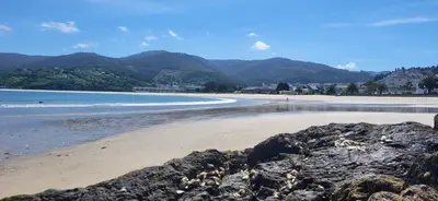 a beach with rocks and the ocean and mountains at Las Gaviotas in Viveiro