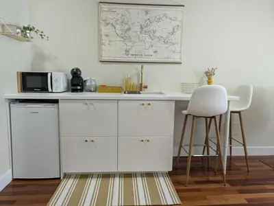 a kitchen with white cabinets and a microwave and a stool at La Mimosa in Puentedeume