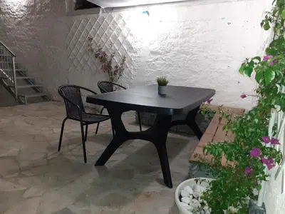 a black table and chairs on a patio with flowers at Cabanela Maitia Jacuzzi privado y barbacoa in Ribadeo