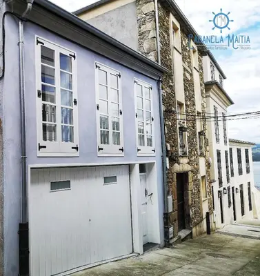 a garage with white doors and windows on a building at Cabanela Maitia Jacuzzi privado y barbacoa in Ribadeo