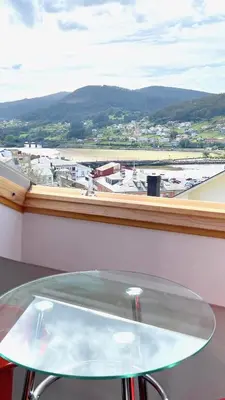 a glass table in front of a window with a view at The Cliffs - ViveMare in Viveiro