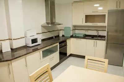a kitchen with white cabinets and a table and a microwave at Alojamiento YASA in Sarria