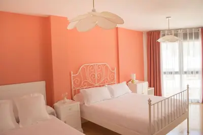 a bedroom with orange walls and a white bed at Alojamiento YASA in Sarria