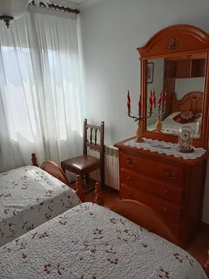 a bedroom with two beds and a dresser with a mirror at Casa Alise in Ribadeo