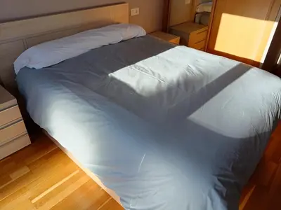 a large white bed in a room with a wooden floor at Apartamento en Puerto de Vega in Navia