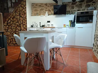 a kitchen with a table and white chairs at A Casiña de Arretén in Padrón