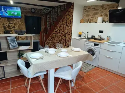 a dining room with a table and chairs and a kitchen at A Casiña de Arretén in Padrón
