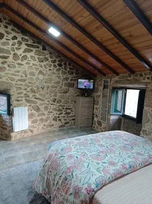 a bedroom with a large bed in a stone wall at A Casiña de Arretén in Padrón