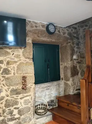 a stone kitchen with a window and a clock on the wall at A Casiña de Arretén in Padrón