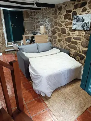 a bed in a room with a stone wall at A Casiña de Arretén in Padrón