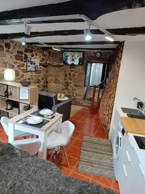 a living room with a table and a kitchen at A Casiña de Arretén in Padrón