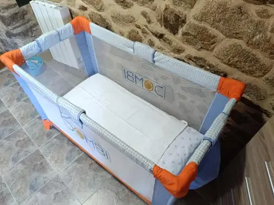 a baby crib with an orange and blue frame at A Casiña de Arretén in Padrón