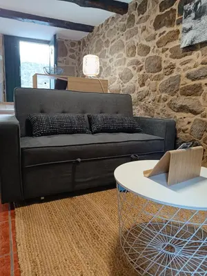 a living room with a black couch and a table at A Casiña de Arretén in Padrón