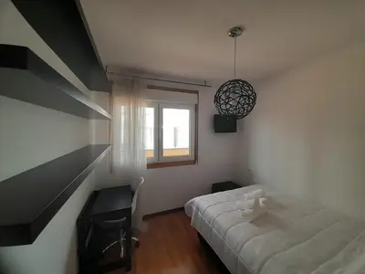 a bedroom with a bed and a desk and a window at EnViveiro a pie de Playa de Covas II in Viveiro