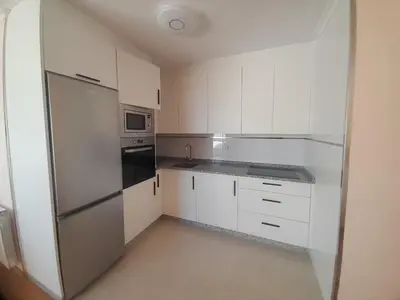 a kitchen with white cabinets and a stainless steel refrigerator at EnBURELA Tus Mejores Vacaciones in Burela de Cabo