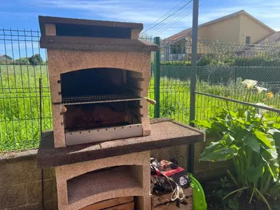 a stone pizza oven sitting in a garden at Casa As Bateas in Sada