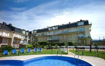 a large apartment building with a swimming pool and blue chairs at Apartamento en Playa de Altar in San Cosme de Barreiros