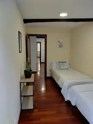 a bedroom with two beds and a wooden floor at A 100 metros Catedral, 3º -Galería -Duplex in Santiago de Compostela