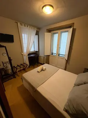 a bedroom with a large bed and two windows at Hotel Real in Santiago de Compostela