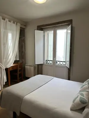 a bedroom with a large bed and two windows at Hotel Real in Santiago de Compostela